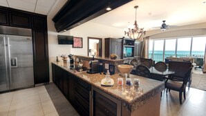 A modern kitchen with a large island, dark cabinetry, stainless steel appliances, and a view to the outside. - Holiday Inn Club Vacations Grand Residences by IHG - All Inclusive (Puerto Morelos)