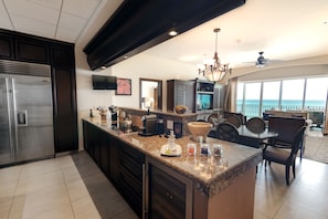 A modern kitchen with a large island, stainless steel appliances, and a dining area with a view. - Holiday Inn Club Vacations Grand Residences by IHG (Puerto Morelos)
