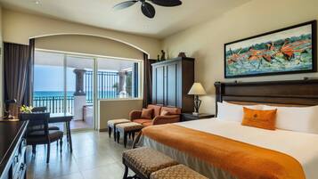 Habitación de hotel con una cama grande, un escritorio, una silla, un sofá y un balcón con vistas al océano.