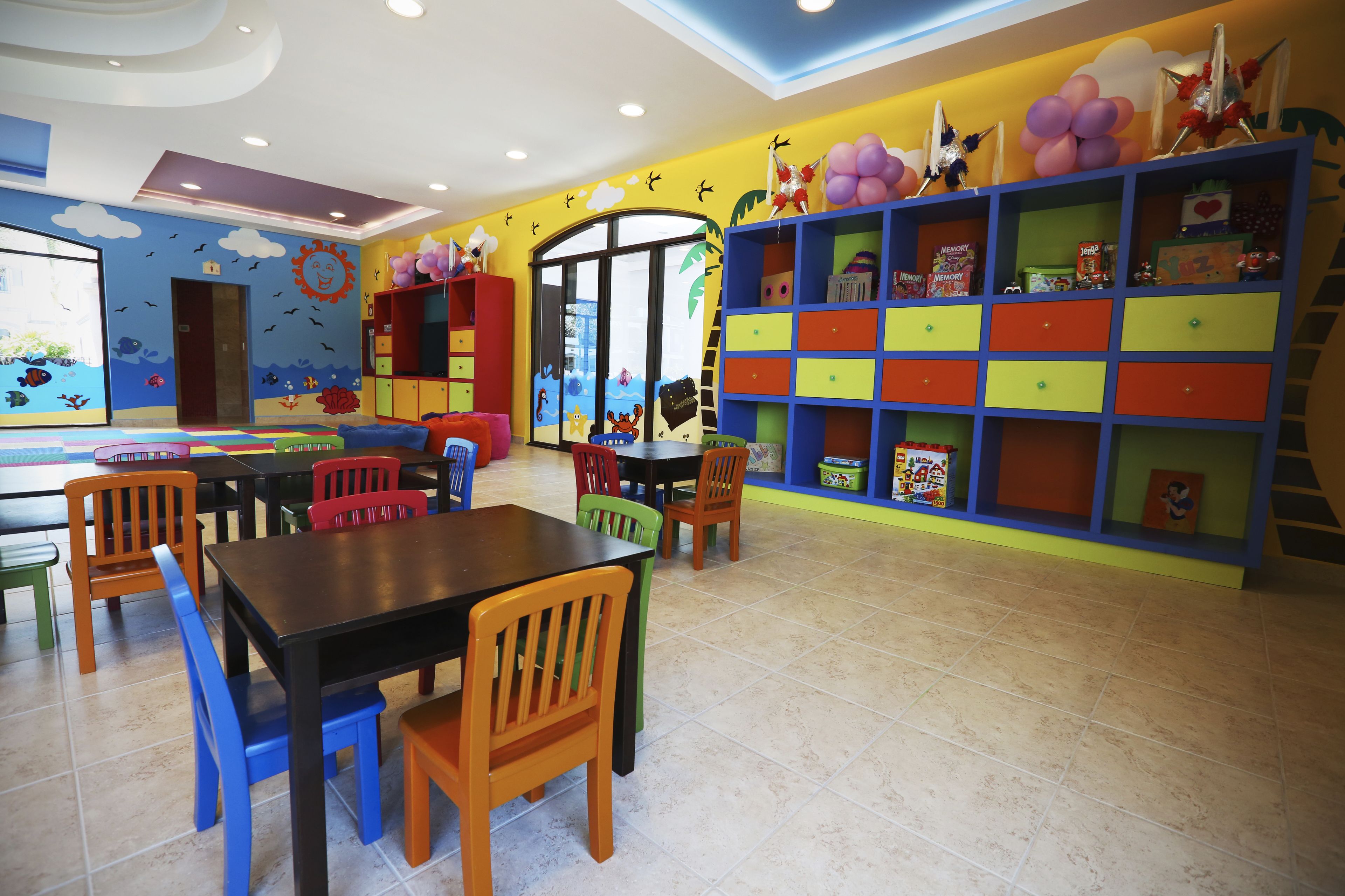 A brightly colored children's playroom with a large bookshelf, a table, and chairs.