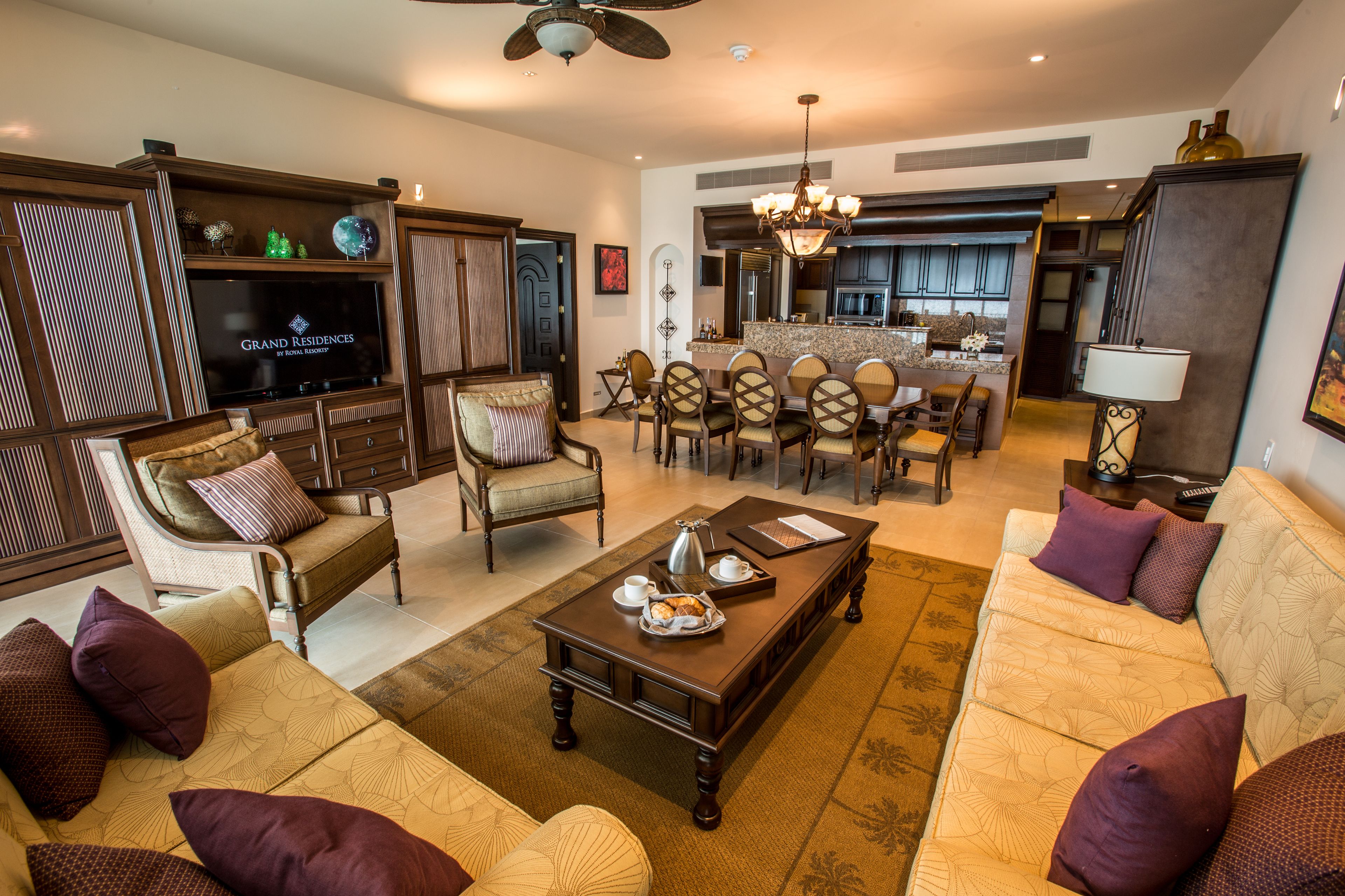 Uma sala de estar ampla com uma televisão de tela grande, assentos confortáveis, uma mesa de centro e uma área de jantar com cadeiras e mesa.
