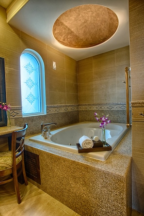 A modern bathroom with a freestanding bathtub, a vanity with a mirror, and a window with decorative glass.