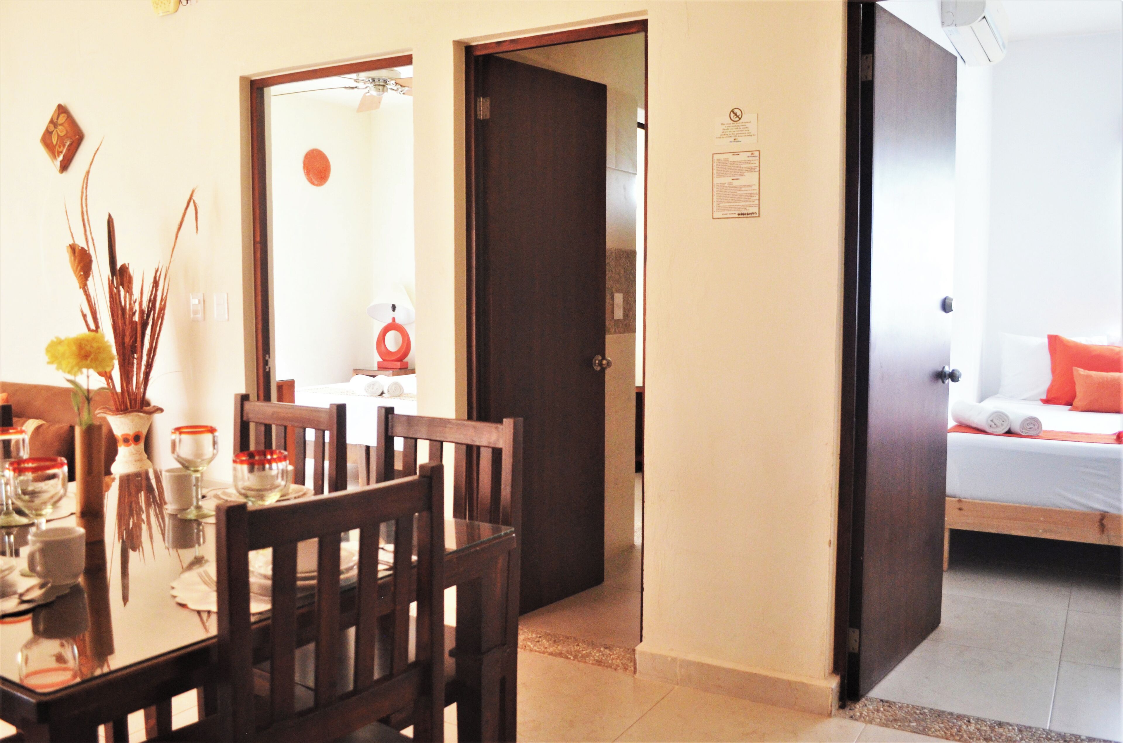 A hotel room with a wooden bed, a small table with chairs, and a dining area with a table set for two.