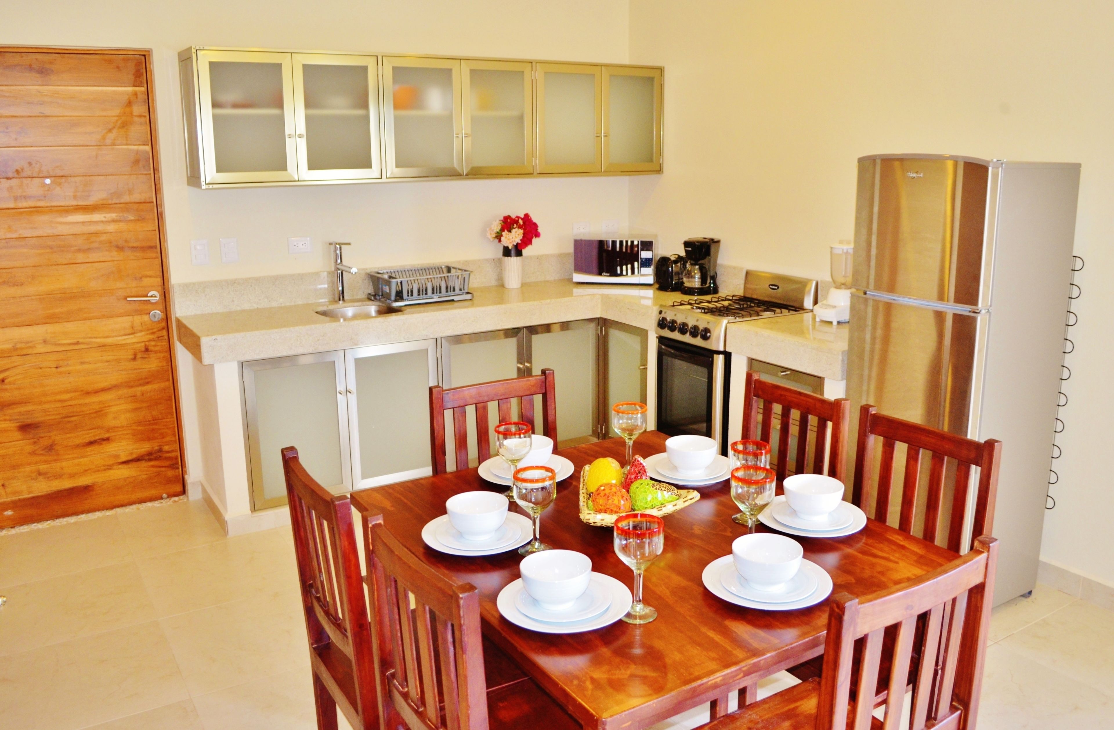 Una cocina compacta con comedor, armarios de madera, refrigerador y estufa.