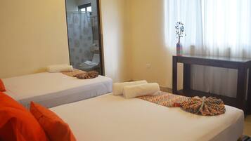 Habitación de hotel con dos camas, una mesita y un espejo.