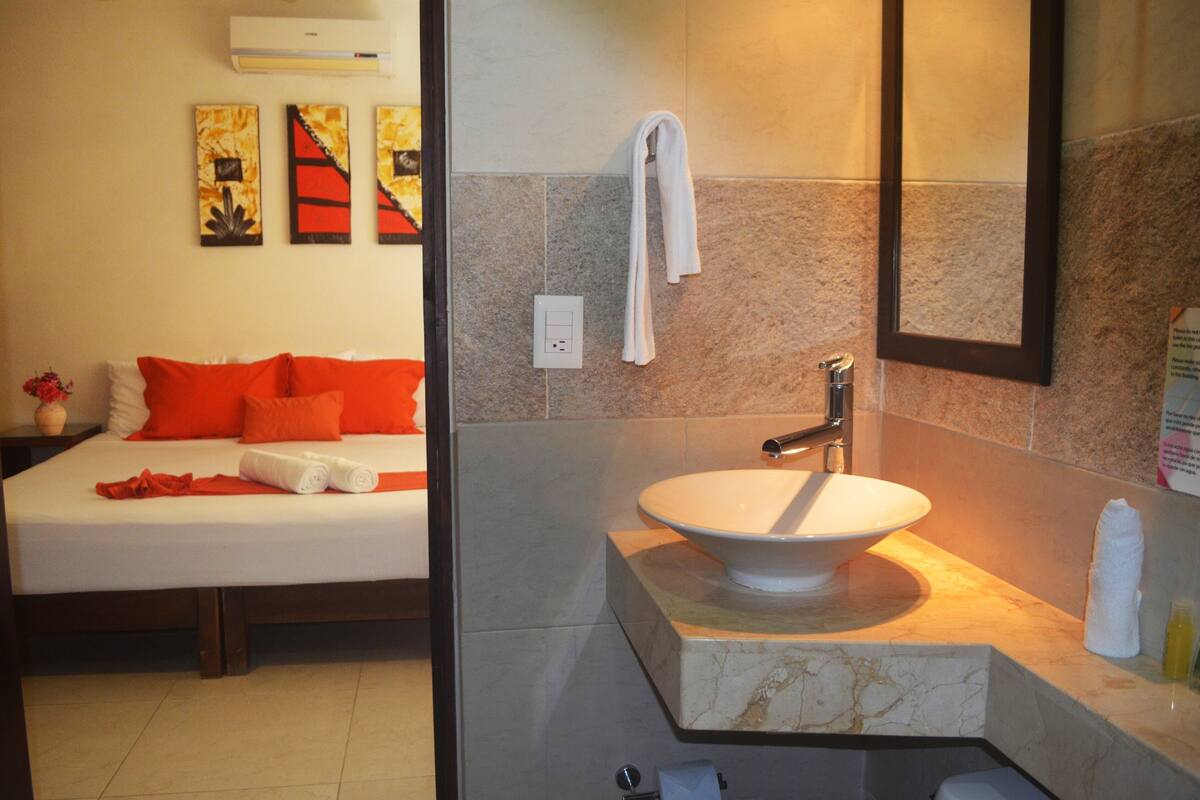 Una habitación de hotel con una cama, un lavamanos blanco y un espejo.