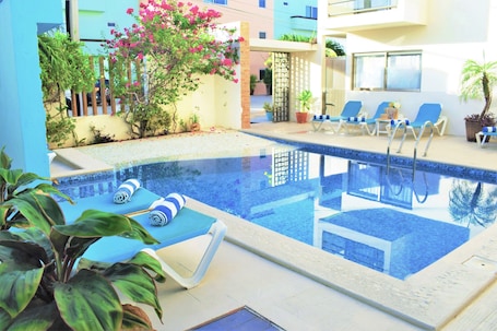 Una piscina al aire libre, sillones reclinables de piscina. Hotel Arrecifes Suites