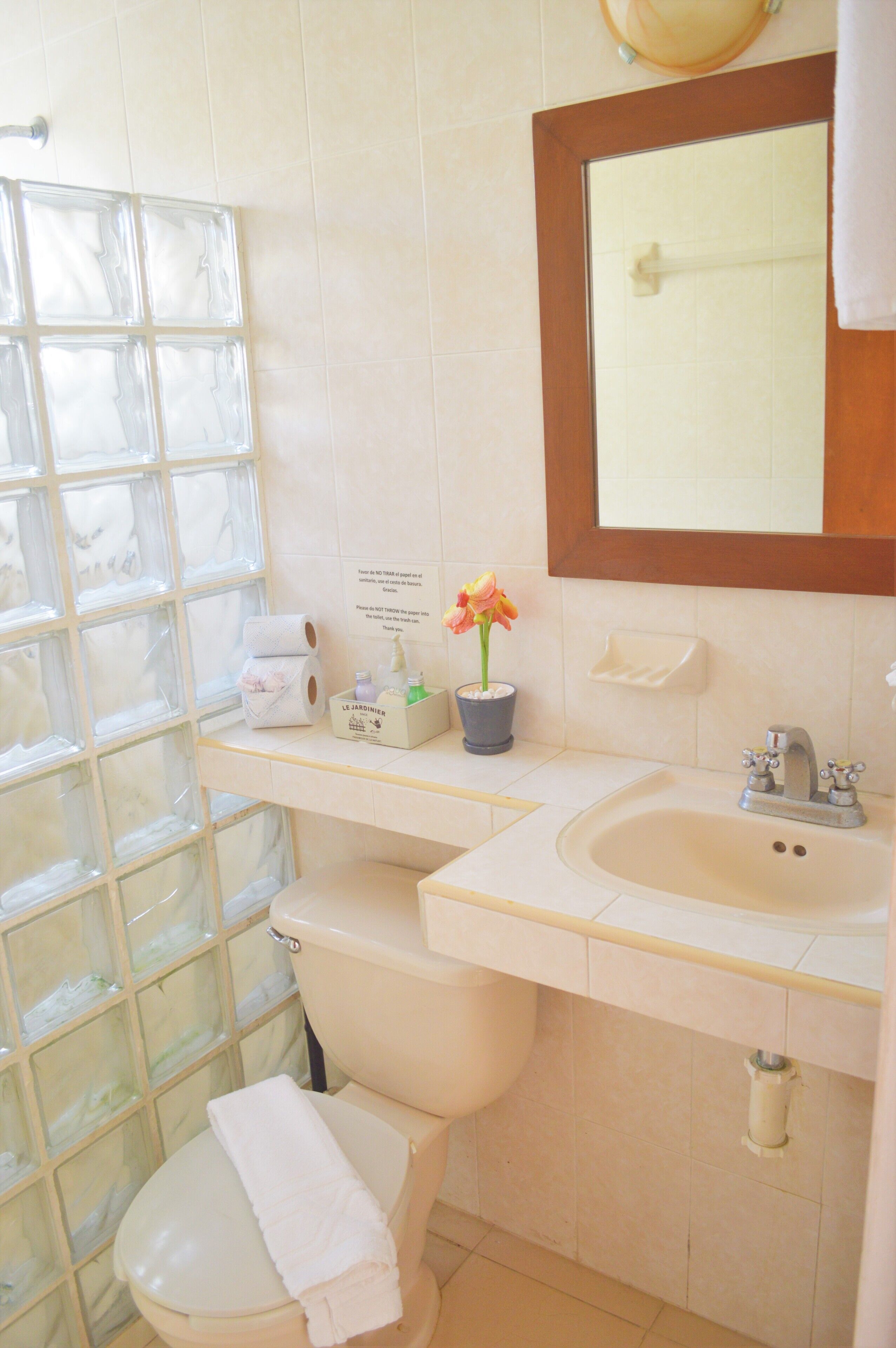 A bathroom with a toilet, sink, and a glass shower enclosure.
