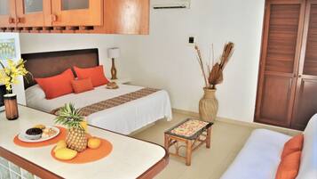 A hotel room with a bed, a small table with a fruit plate, a sofa, and wooden cabinets.