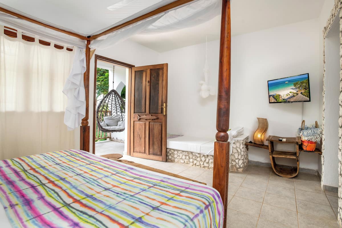 Une chambre à coucher avec un lit, une porte en bois, un téléviseur et une vue sur l’extérieur.
