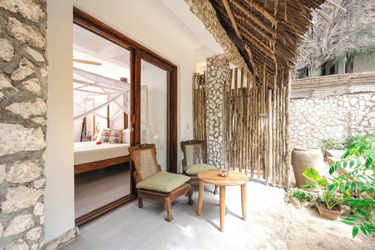 Un espace extérieur accueillant, aménagé avec un mur en pierre, des meubles en bois et des plantes en pot.