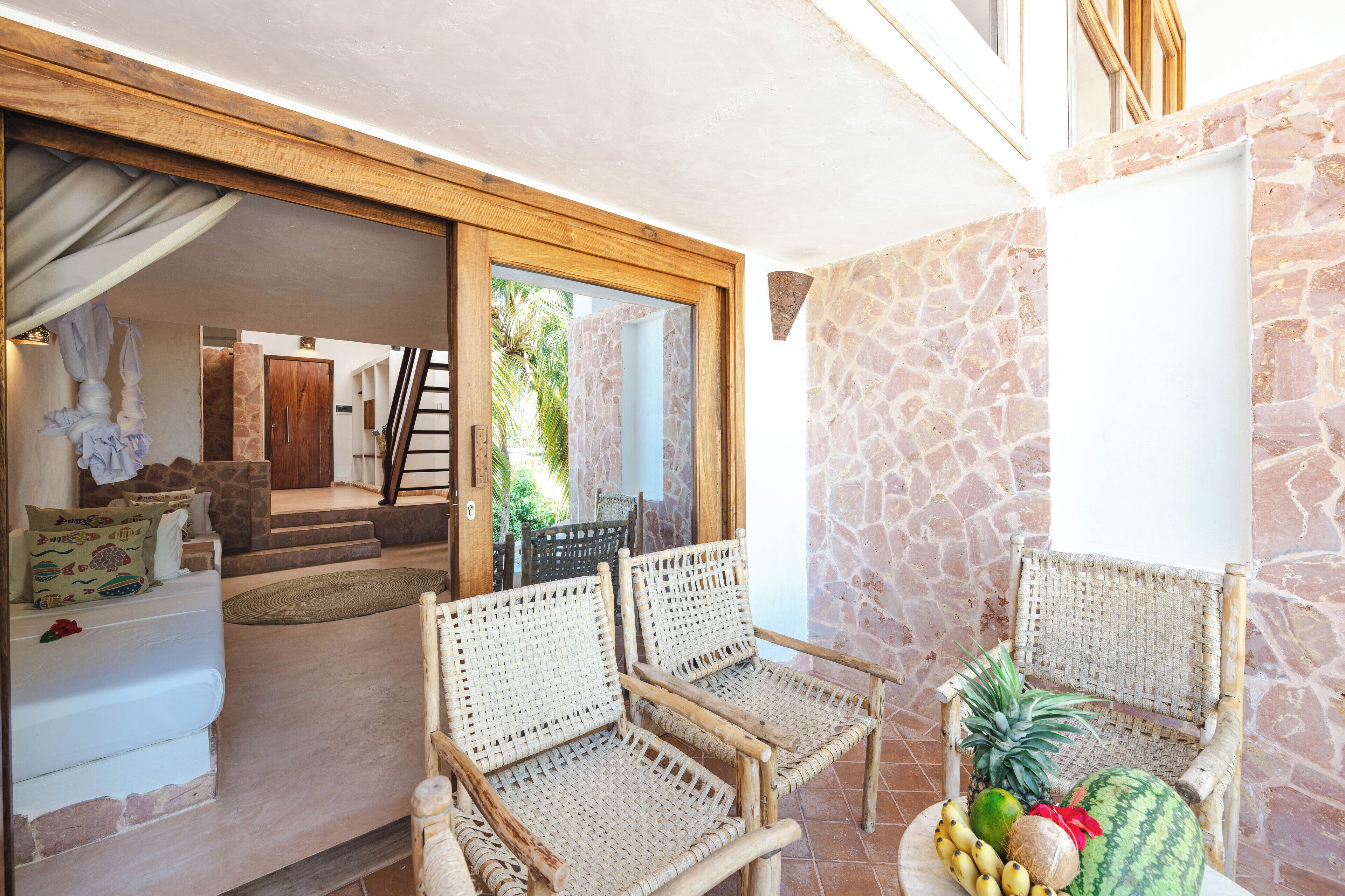 Una habitación con sillas de mimbre, una cama y una mesa con frutas.