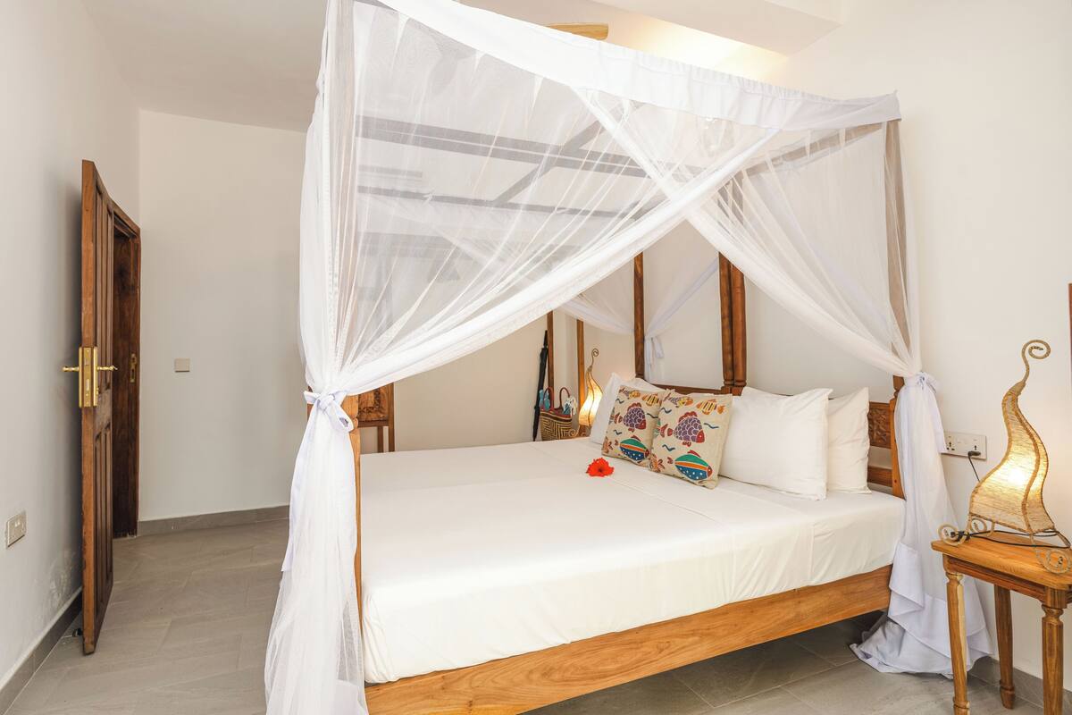 Une chambre à coucher avec un lit à baldaquin, une table de chevet en bois et une lampe de chevet.