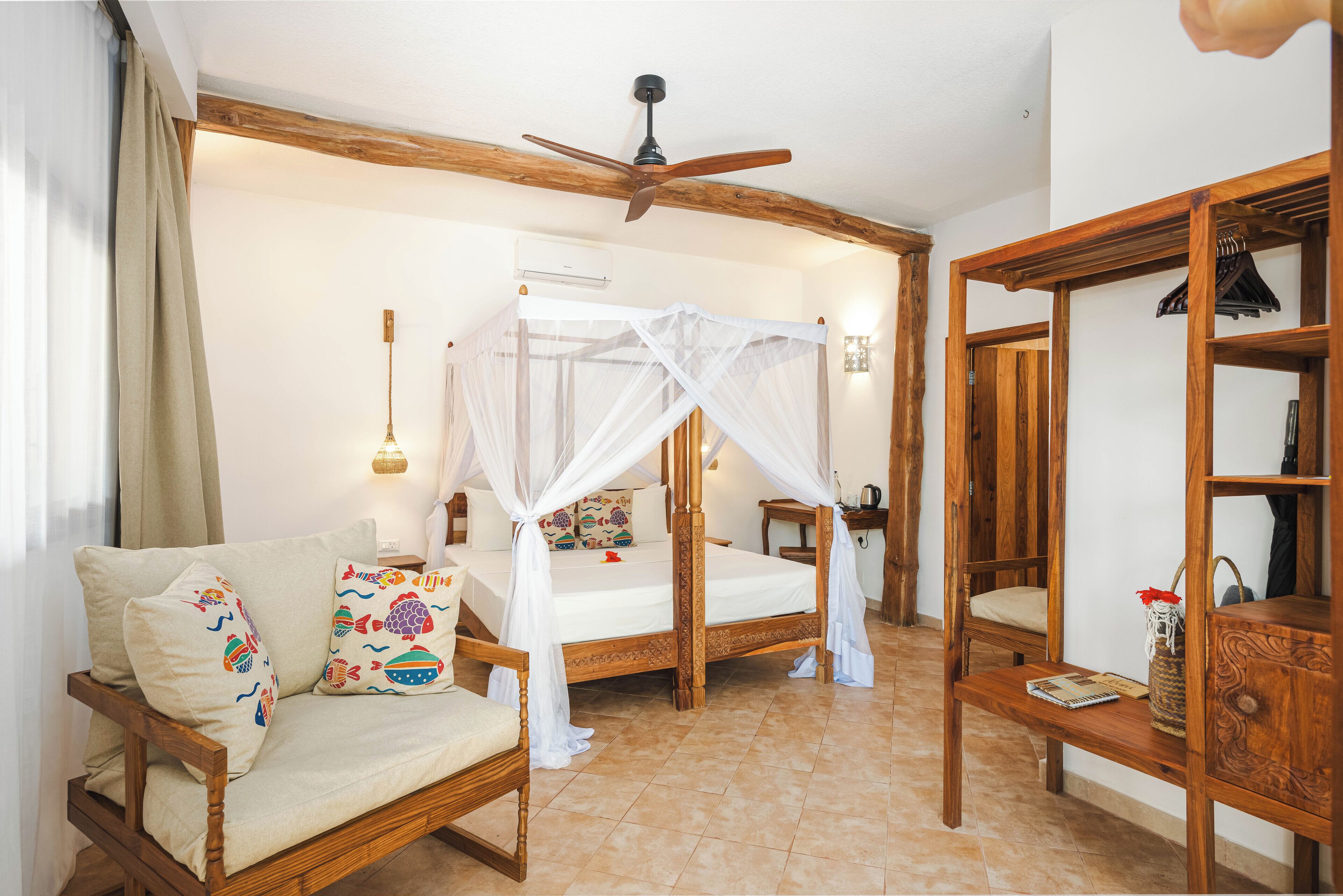 A bedroom with a four-poster bed, a wooden bench, a bedside table, and a ceiling fan.