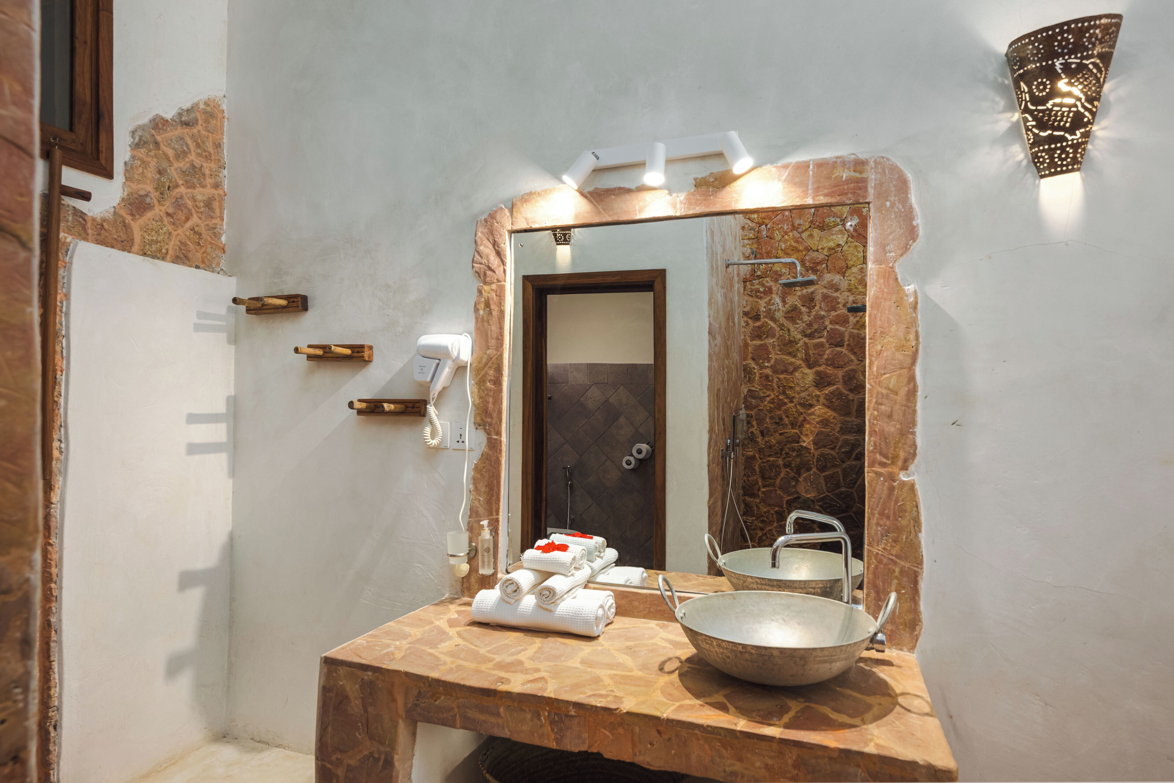 A bathroom with a stone countertop, a large mirror, a sink, and a towel rack.