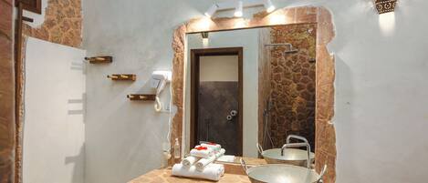 A bathroom with a stone countertop, a large mirror, a sink, and a towel rack.