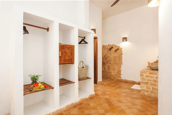 Un pasillo con paredes blancas, estantes de madera y una pared de piedra.