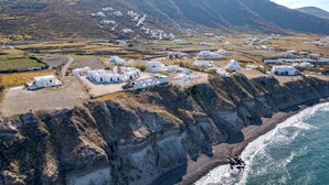A coastal village with white buildings, a cliffside, and a beach. - Agia Irini (Santorini)