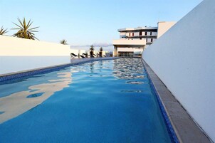 Una piscina al aire libre, sillones reclinables de piscina