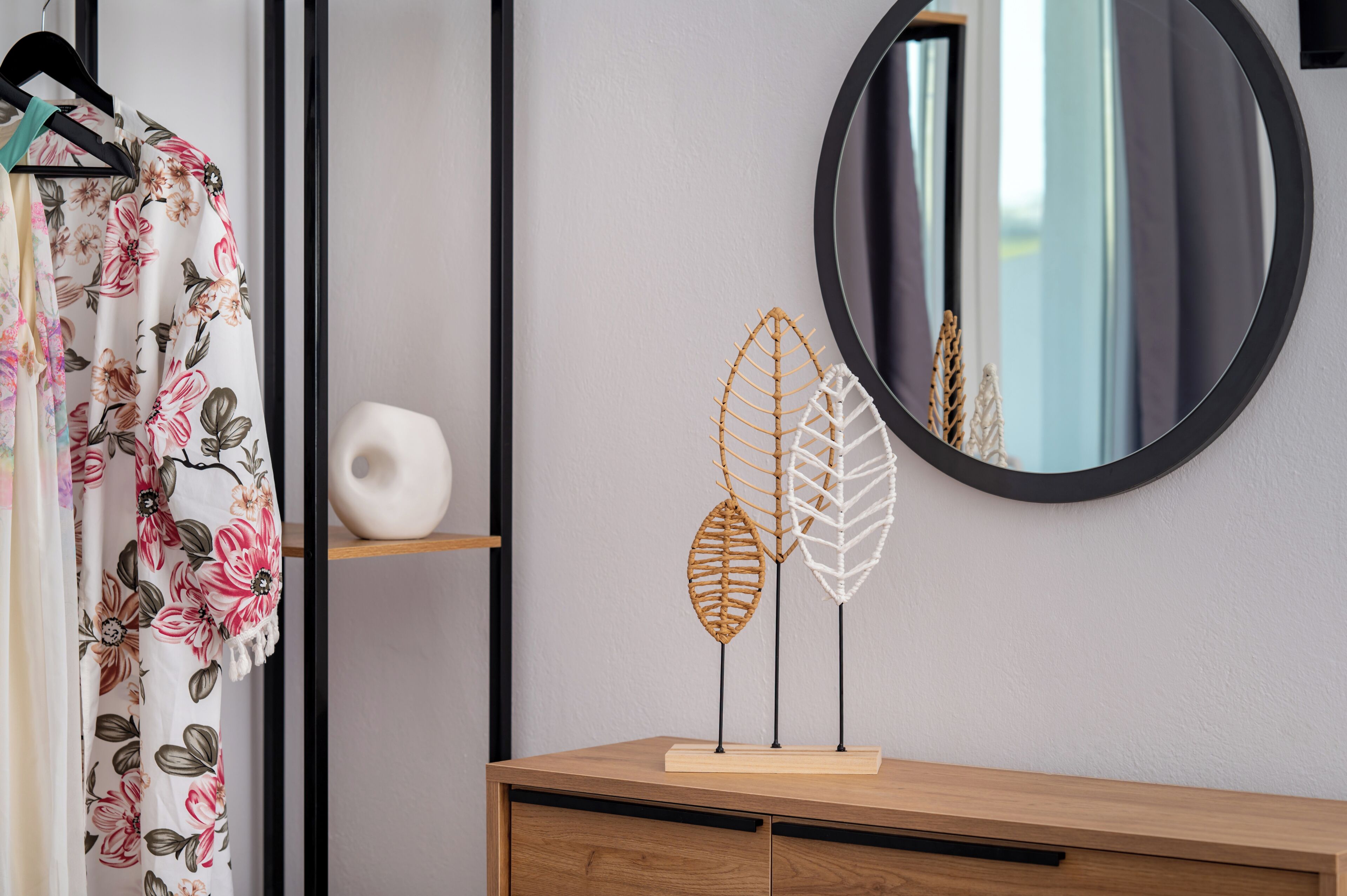 A room with a wooden dresser, a mirror, and a floral curtain.