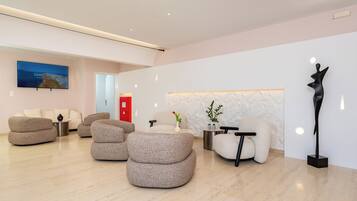 Un hall d’entrée moderne avec des canapés, un téléviseur, un mur en marbre et une sculpture.