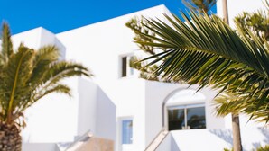 A modern white building with a staircase and palm trees. - Nikos Hotel (Santorini)