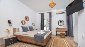 A modern bedroom with a wooden bed, a bedside table, a mirror, a small stool, and a wall-mounted air conditioner. - Nikos Hotel (Santorini)
