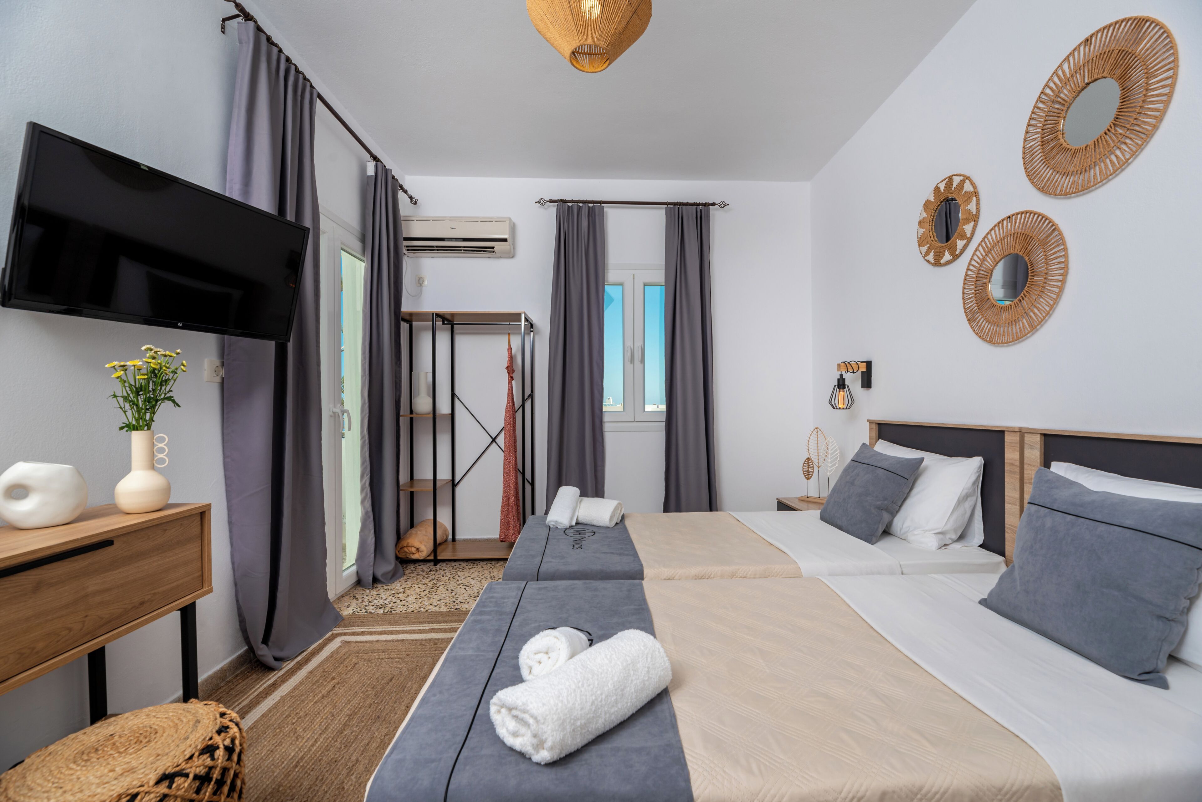 A hotel room with a bed, a TV, a desk, and a window.