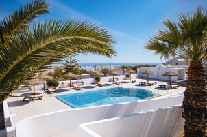 Piscina en la azotea con sillones y sombrillas, con vistas a un paisaje costero.