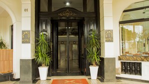 La entrada del Hotel Atlantic, con puertas dobles, plantas en macetas y un piso de mármol.