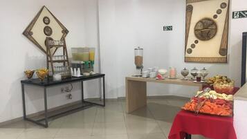 Una habitación con una barra de desayuno, que incluye una mesa con diferentes alimentos y una estación de café.