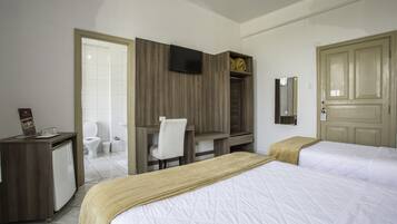 A hotel room with a bed, a desk, a chair, a TV, a wardrobe, a bathroom, and a door.