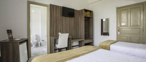 A hotel room with a bed, a desk, a chair, a TV, a wardrobe, a bathroom, and a door.
