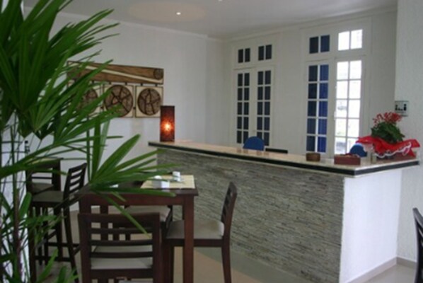 A kitchen with a stone countertop, wooden chairs, and a potted plant. - Atlântico Hotel (Santos)