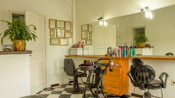 Un salón con dos sillas, un espejo y una barra con diversos productos para el cabello.