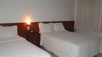 A hotel room with two beds, a nightstand, and a wall-mounted lamp.