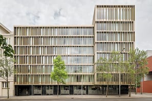 Un edificio moderno con fachada de diseño geométrico, grandes ventanales y tejado plano.