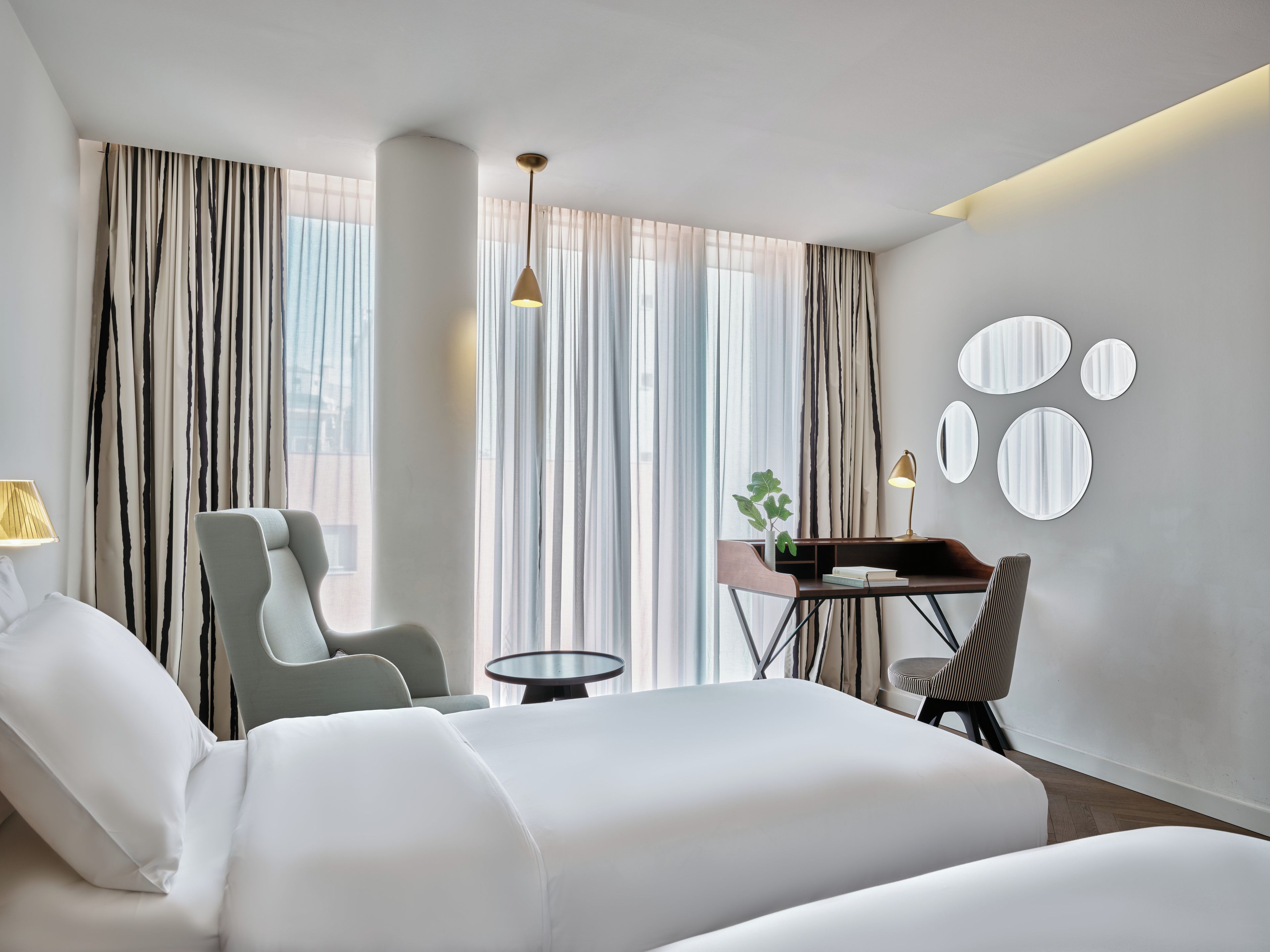 Una habitación de hotel con una cama, una silla, un escritorio y una lámpara.