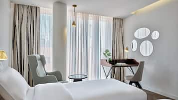 Una habitación de hotel con una cama, una silla, un escritorio y una lámpara.