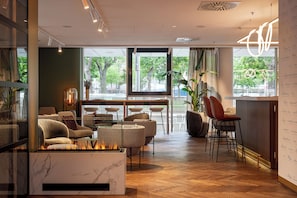 Un interior moderno con chimenea, zona de estar y ventanas amplias con vistas al exterior.