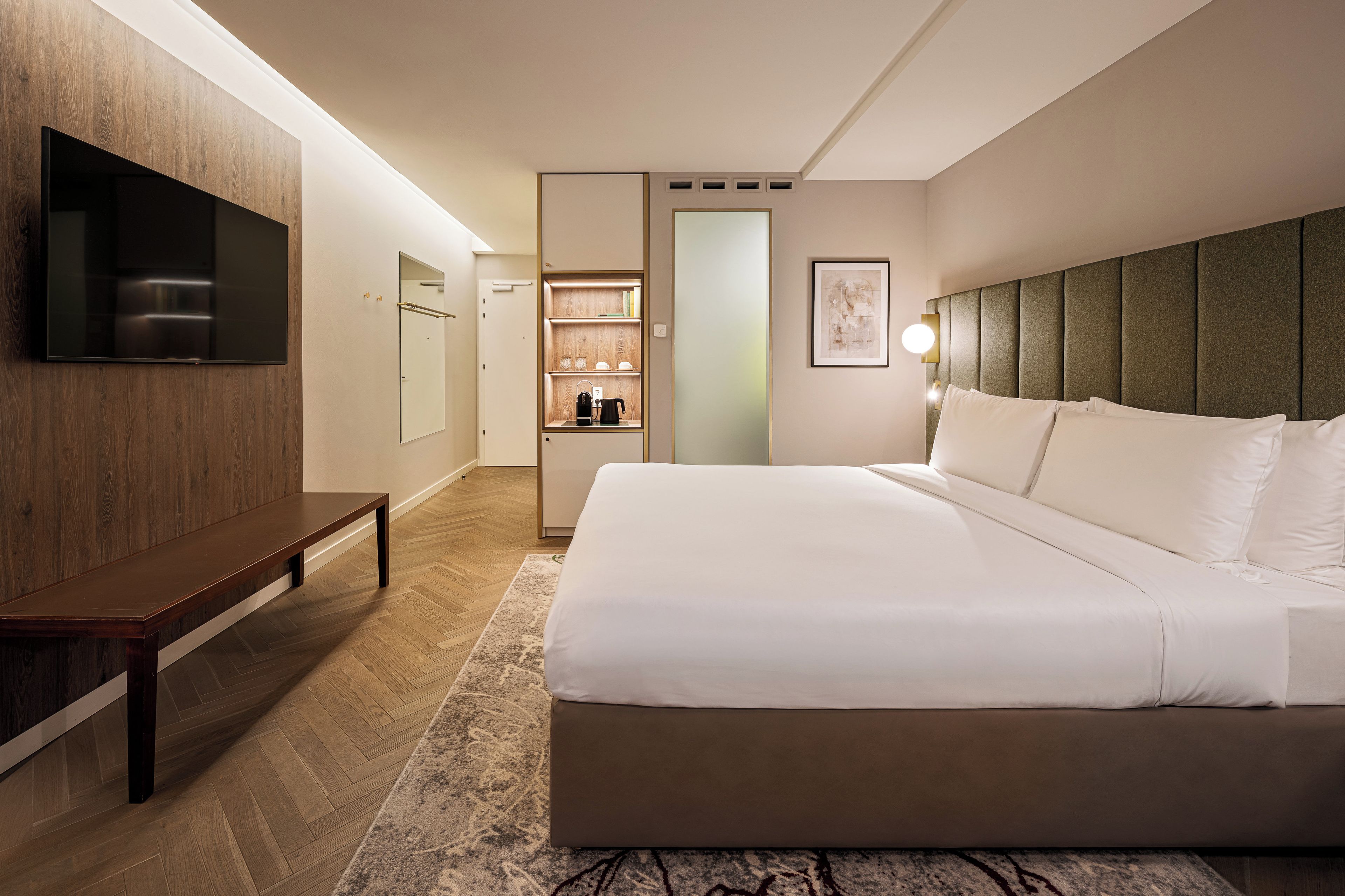 Una habitación de hotel con cama, televisor, armario y baño.