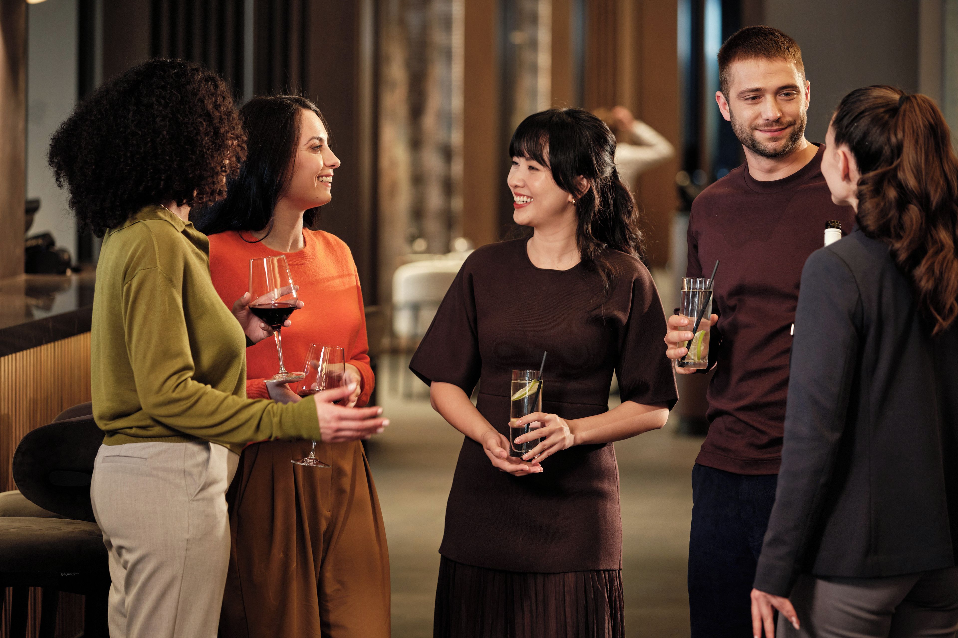 Un grupo de personas en un ambiente social, quizás un bar o una zona de bar, con bebidas en la mano.