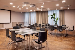 A conference room with a large table, multiple chairs, a projector screen, and a plant. - Crowne Plaza Vienna by IHG (Vienna)