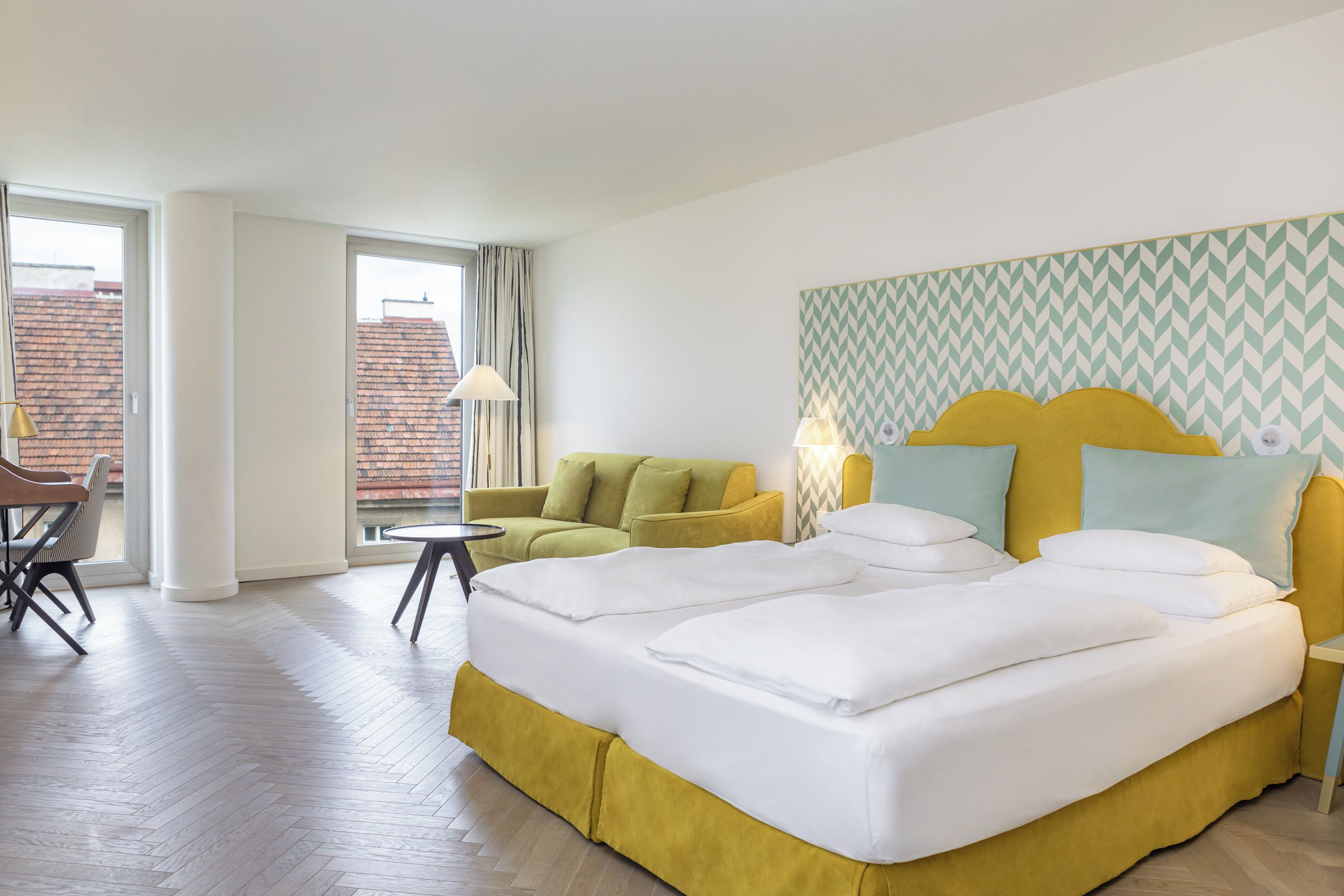 A hotel room with a bed, a sofa, a small table, and a chair.