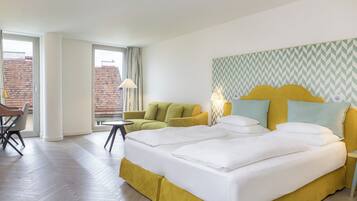 A hotel room with a bed, a sofa, a small table, and a chair.