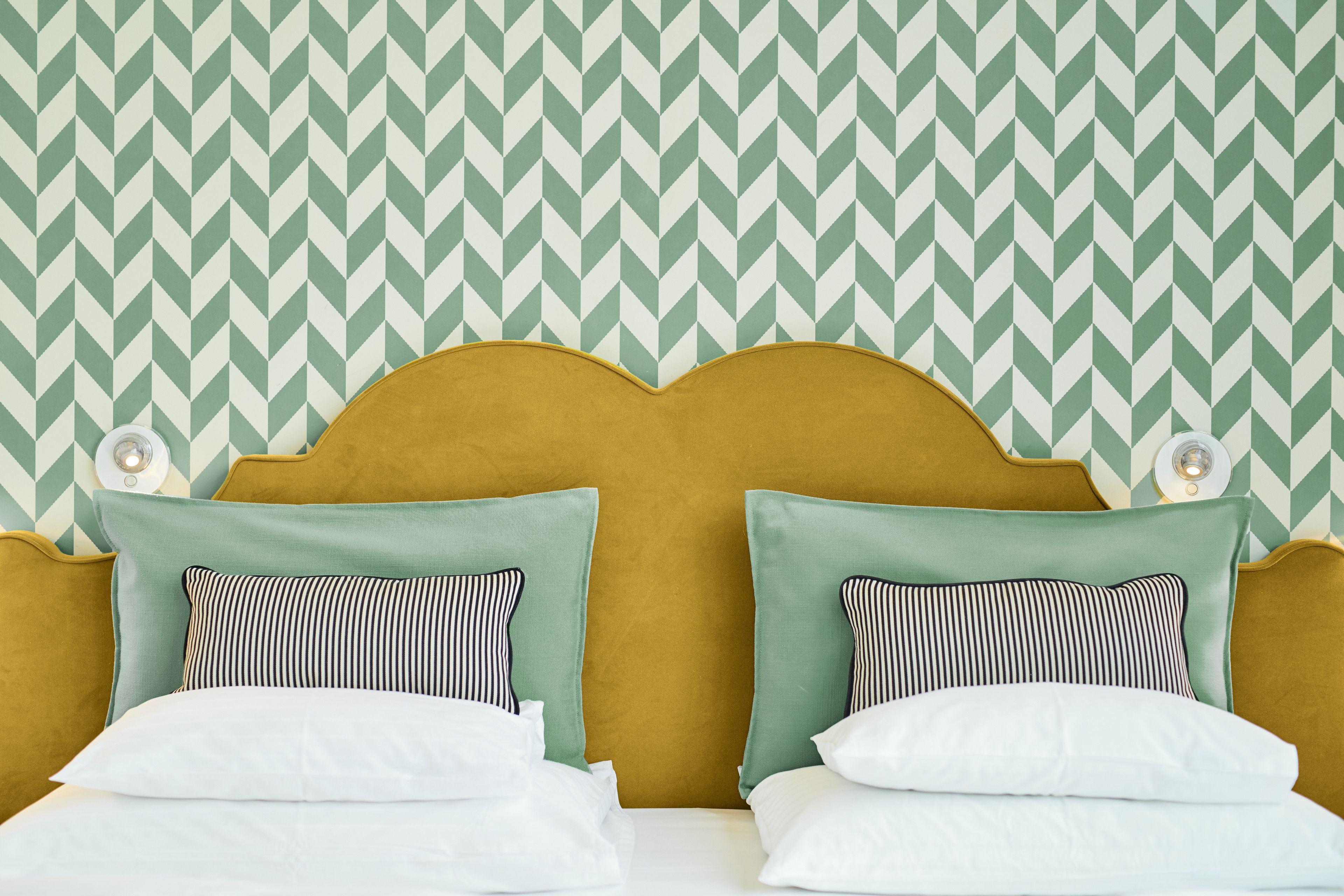 Ein Bett mit Kopfteil, zwei Kissen und eine Wand mit Zickzackmuster.