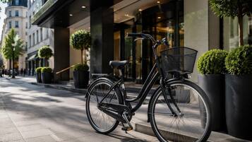 Ein schwarzes Fahrrad mit Korb steht an einem Stadtbordstein.