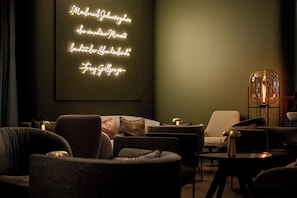 A dimly lit lounge area with a neon sign, comfortable seating, and a table with a lamp. - Crowne Plaza Vienna by IHG (Vienna)