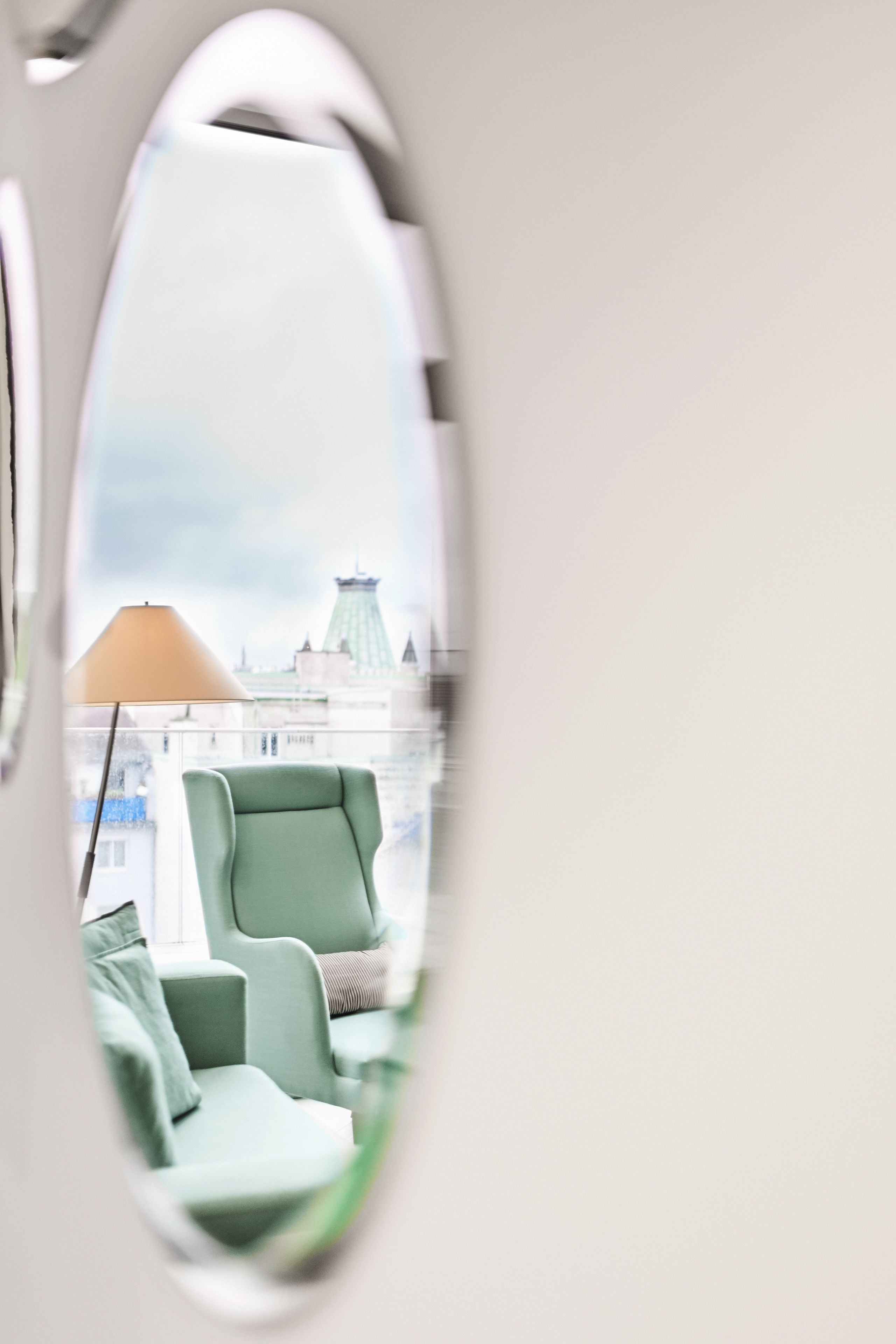 A view through a window with a chair and a lamp inside.