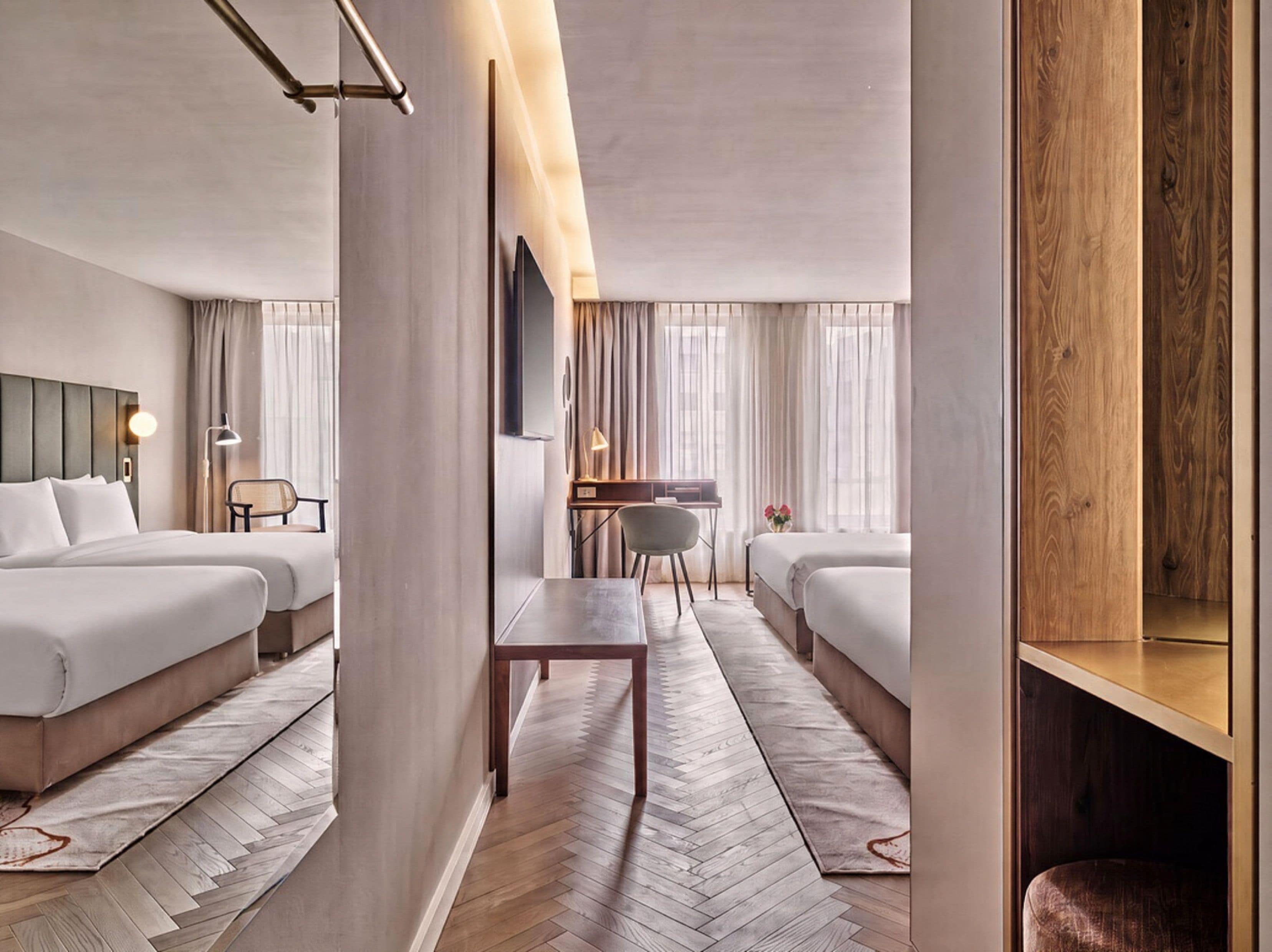 Ein Hotelzimmer mit zwei Betten, einem Schreibtisch und einem Stuhl.